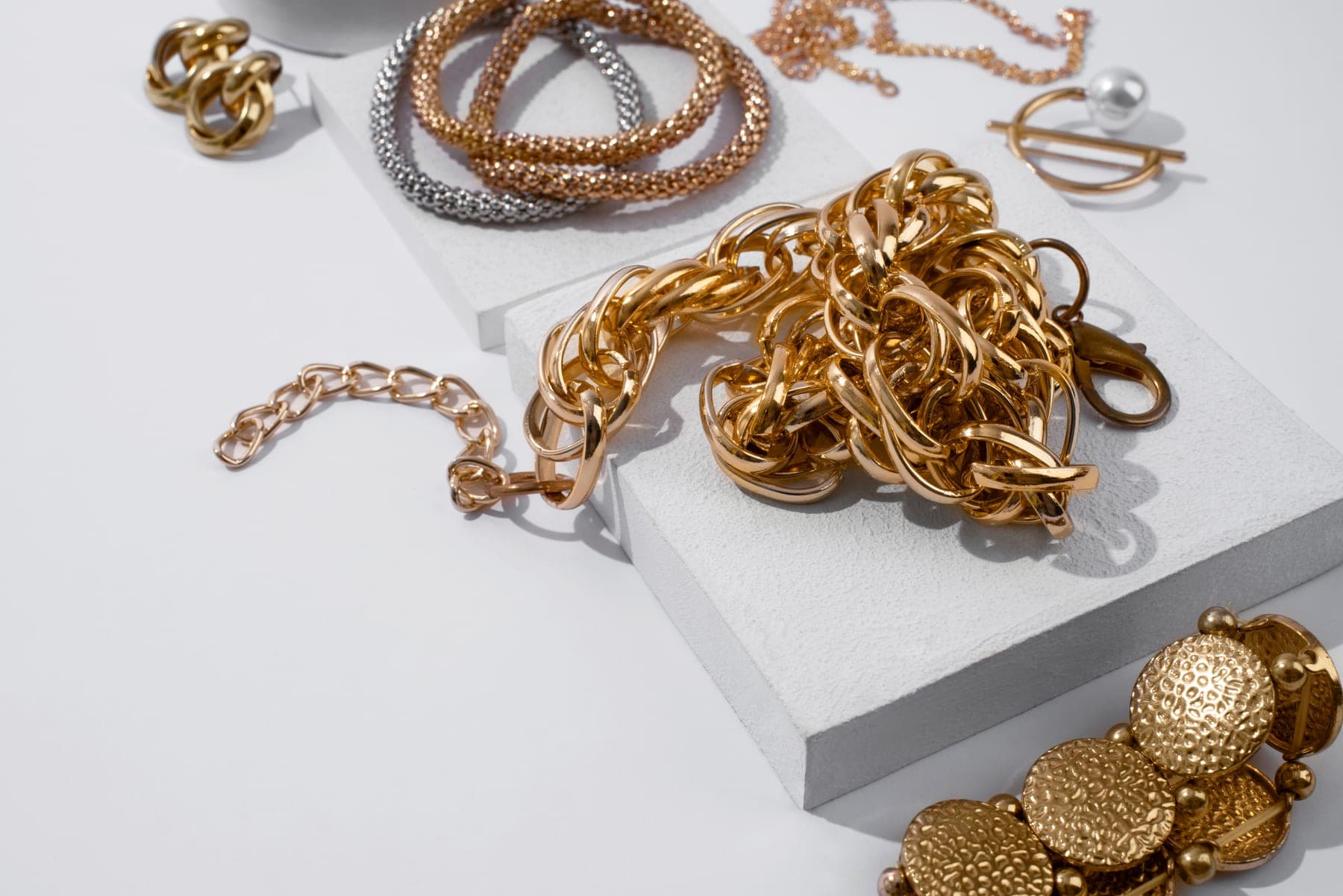 Gold chains and bracelets gathered on white blocks